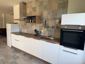 A modern kitchen with a built-in oven, a coffee maker, and a sink. - New, cosy and adult only app in a beautiful village with a lake view (Béznar)