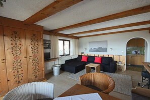 Ein gemütliches Wohnzimmer mit einer Couch, einem Esstisch und einer Küche im Hintergrund.