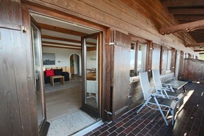 Eine Holzhütte mit Veranda, Essbereich und Wohnzimmer mit Sofa und Tisch.