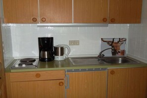 Eine Küche mit Holzausstattung, einer Kaffeemaschine, einem Wasserkocher und einem Spülbecken.