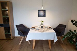 A dining area with a table set for two, a potted plant, and a framed artwork on the wall. - Holiday apartment with 1 bedroom (Hopfen am See)