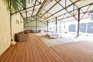 A covered outdoor area with a wooden deck, seating, and a table with wheels.