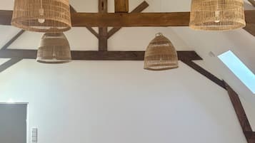 Una habitación con tres camas, vigas de madera y lámparas de techo tejidas.