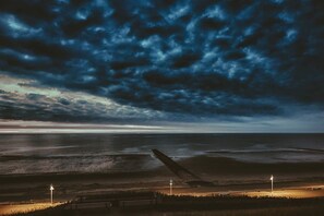 Eine Küstenlandschaft mit Strand, einem Steg und einem stürmischen Himmel.