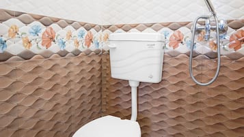 A bathroom with a toilet, a shower, and a patterned wall.