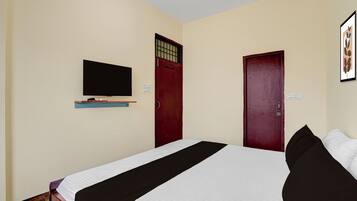 Una habitación con una cama, un televisor montado en la pared y dos puertas.