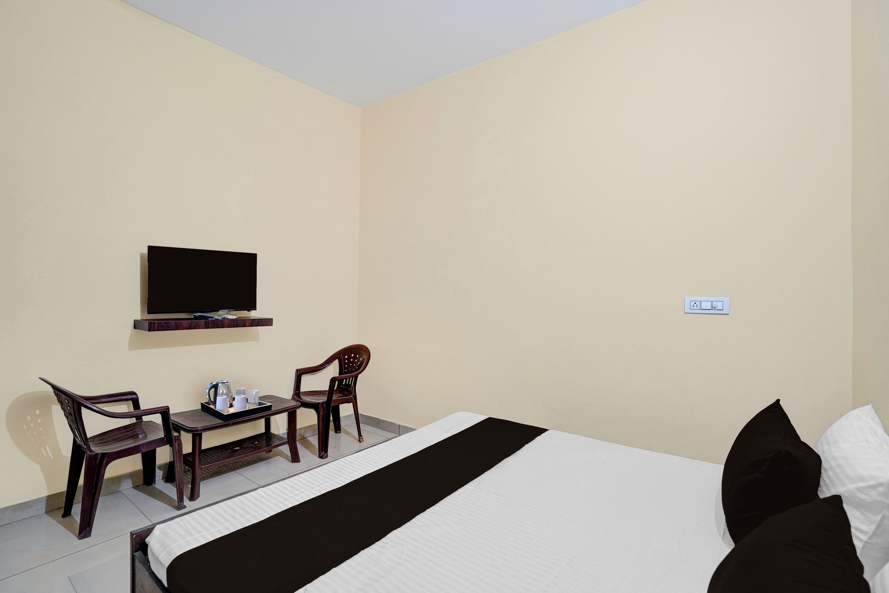 Una habitación de hotel con una cama, un escritorio con una silla, un televisor y un enchufe.