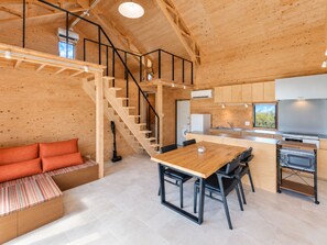 A modern interior with a wooden staircase, a dining area, and a kitchen. - One Roof SHIRAHO (Ishigaki)