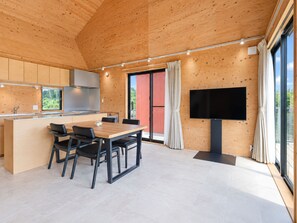 A modern kitchen with wooden cabinetry and a dining area with a table and chairs. - One Roof SHIRAHO (Ishigaki)