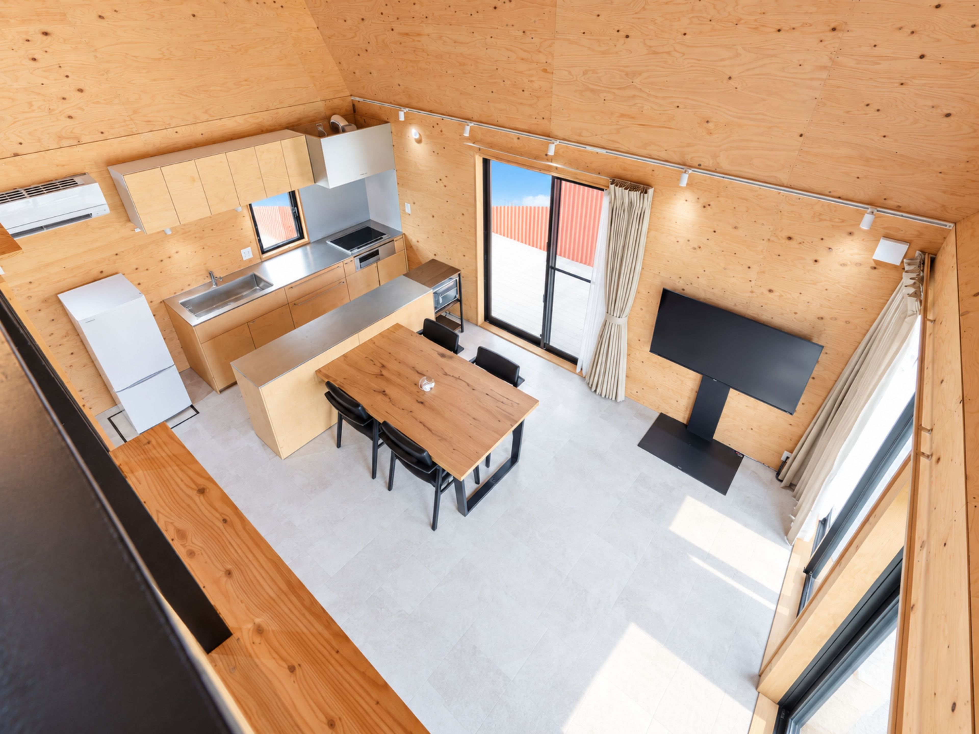A modern kitchen with a central island, a dining area with a table and chairs, and a built-in TV.
