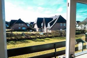 A residential area with houses, a grassy lawn, and a wooden fence. - Holiday apartment with 2 bedrooms (Wenningstedt-Braderup)