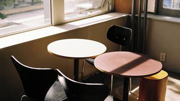 A small, enclosed seating area with two tables and chairs, a window, and a view of the street outside.