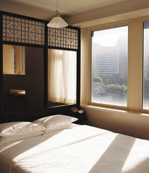 A hotel room with a large window, a bed with white linens, and a hanging light fixture. - The Magpie Hotel (Seoul)