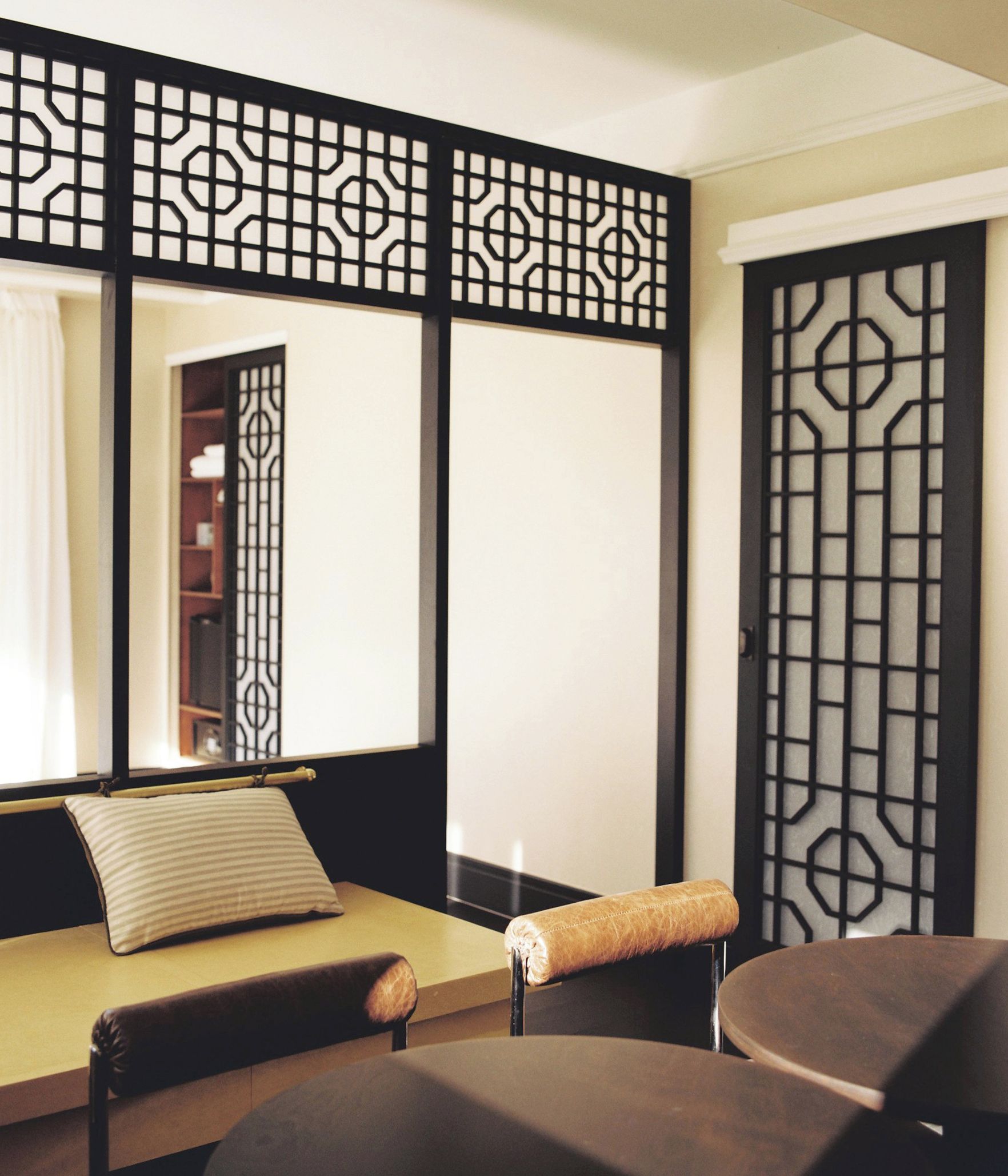 A room with a sofa, a chair, and a decorative partition with a geometric pattern.