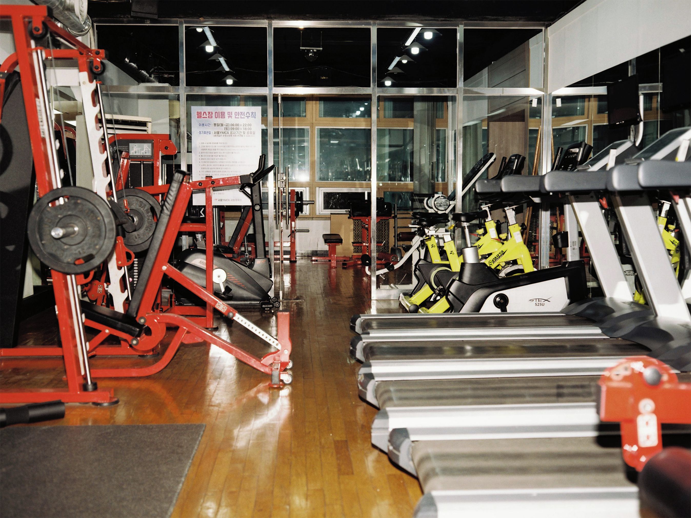 A gym with exercise equipment, including treadmills and weight machines, and a sign with information.