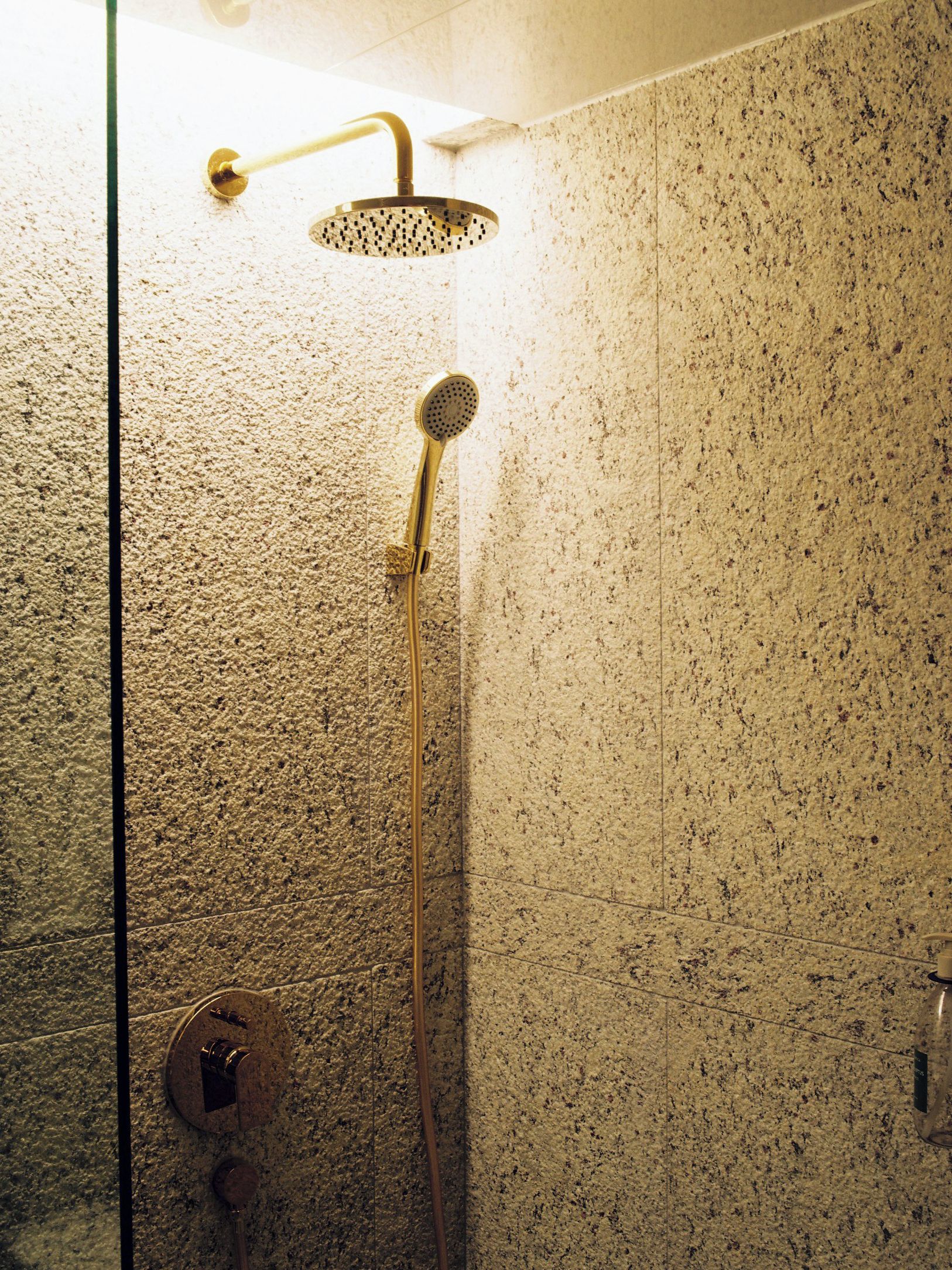 A shower with a handheld showerhead and a wall-mounted showerhead, both with a metallic finish.