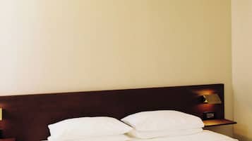Ein Hotelzimmer mit einem Bett, Kissen, einem Nachttisch und einer Wandlampe.