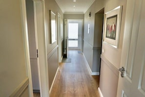 A hallway with a wooden floor, white walls, and doors on both sides. - House Rungholt Holiday Apartment 8 (Wenningstedt-Braderup)