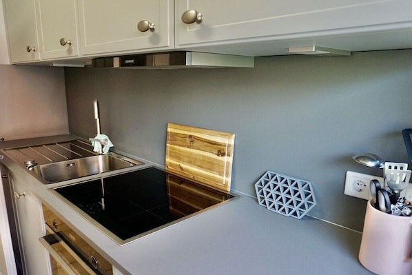 A modern kitchen with a built-in stove, a sink, and a wooden cutting board. - House Rungholt Holiday Apartment 8 (Wenningstedt-Braderup)