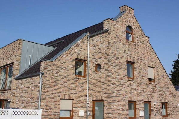 A brick building with a gabled roof, multiple windows, and a visible chimney. - Holiday apartment with 3 bedrooms (Borkum)