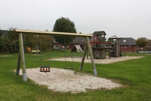 Een speeltuin met schommels en een klimrek.