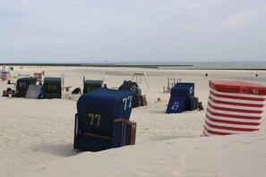 A beach with numbered beach chairs and umbrellas. - Holiday apartment with 3 bedrooms (Borkum)