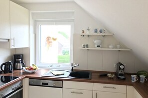 Eine Küche mit Fenster, einer Kaffeemaschine, einem Wasserkocher und einer Obstschale.