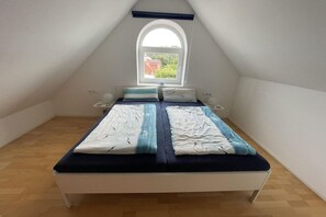 Ein Zimmer mit einem Bett, einem Fenster und Blick auf Grün.