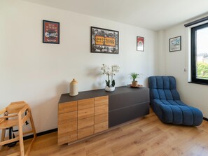 A modern living room with a wooden cabinet, a blue armchair, and decorative wall art. - Modern Elegance at Residence 41 - Heart of Bastogne (Bastogne)
