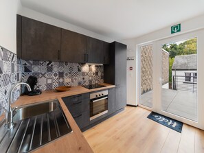 A modern kitchen with a stainless steel sink, a built-in oven, and a patterned backsplash. - Modern Elegance at Residence 41 - Heart of Bastogne (Bastogne)