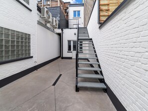 Un carrer estret amb una escala metàl·lica que condueix a l'entrada d'un edifici.