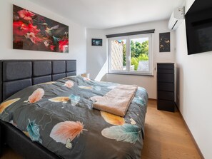 A bedroom with a bed, a window with a view, and a painting on the wall. - Modern Elegance at Residence 41 - Heart of Bastogne (Bastogne)