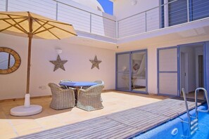 Ein Poolbereich mit Korbmöbeln, einer Meerstern-Dekoration und einem Deckenventilator.