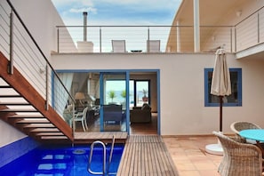 A pool area with a wooden deck, a lounge chair, and a table with an umbrella.