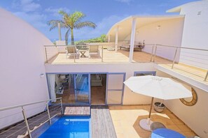 Un edifici residencial de dues plantes amb piscina, zona d'estar a l'aire lliure i vistes a palmeres.