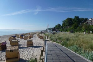 Ein Strand mit einer Holzpromenade, Liegestühlen und einer Flagge.
