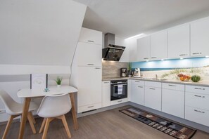 Eine moderne Küche mit weißen Schränken, einem Einbauofen und einer Kaffeemaschine.