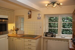 A kitchen with white cabinets, a toaster, a kettle, and a window with greenery outside. - Keitumer Chaussee 5 Holiday Apartment 1 (Westerland)