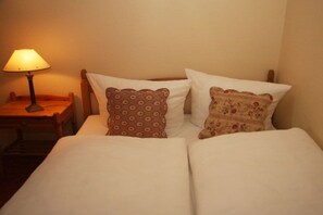 A bed with two pillows, a nightstand with a lamp, and a wooden headboard. - Keitumer Chaussee 5 Holiday Apartment 1 (Westerland)