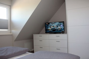 A bedroom with a TV on a dresser, a window, and a bed. - Holiday apartment in Sylt with 3 bedrooms (Westerland)