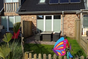 A residential property with a patio area, outdoor seating, and a butterfly decoration. - Holiday apartment in Sylt with 3 bedrooms (Westerland)