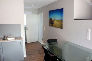 A modern kitchen with a glass-top dining table, a sink, and cabinets. - Holiday apartment in Sylt with 3 bedrooms (Westerland)