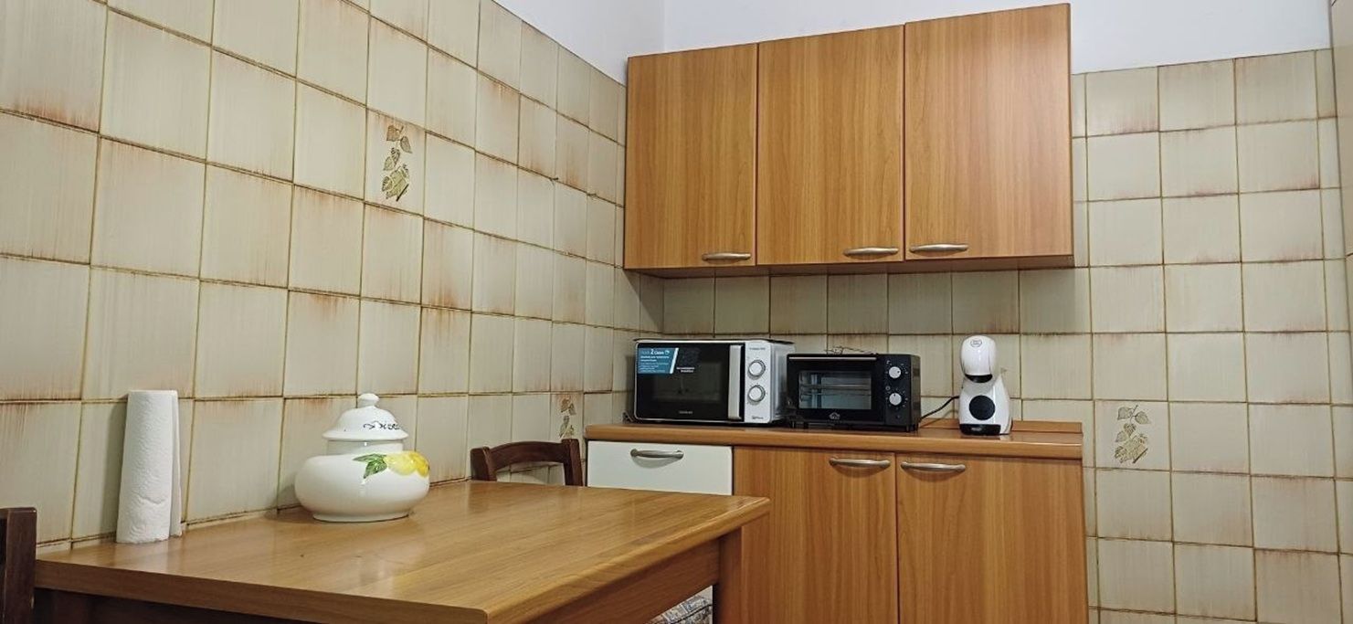 Una cocina con armarios de madera, un microondas, un tostador y una tetera sobre la encimera.