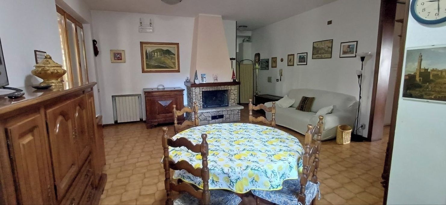 Ein Essbereich mit rundem Tisch, Stühlen, Kamin, einer Couch und einer Wanduhr.