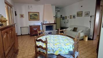 Ein Essbereich mit rundem Tisch, Stühlen, Kamin, einer Couch und einer Wanduhr.