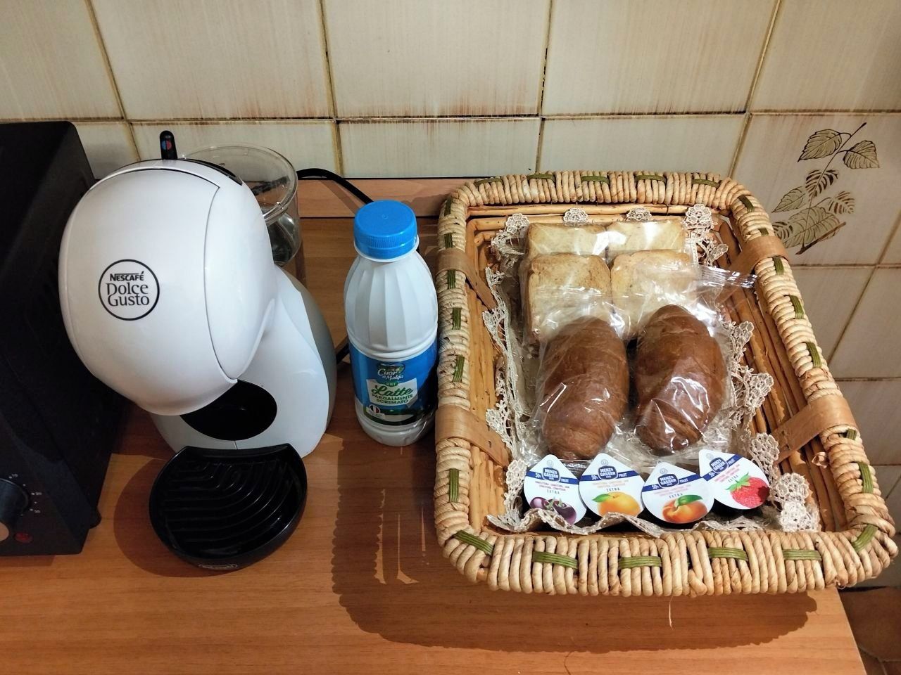 Eine Küchenarbeitsplatte mit einer Kaffeemaschine, einer Milchflasche und einem Korb, der Brot und Milchprodukte enthält.