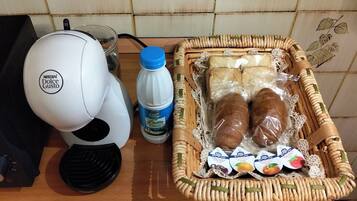 Eine Küchenarbeitsplatte mit einer Kaffeemaschine, einer Milchflasche und einem Korb, der Brot und Milchprodukte enthält.