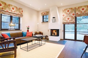 A modern living room with a fireplace, leather sofa, and large windows. - Klingenburger bakery (Jettingen-Scheppach)