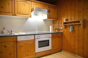 A kitchen with wooden cabinets, a Bosch dishwasher, a built-in oven, and a stainless steel range hood. - Guesthouse Schmid & Reitzner 2 (Immenstadt)