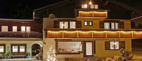 Un edificio de dos plantas con balcón, comedor y un árbol de Navidad.